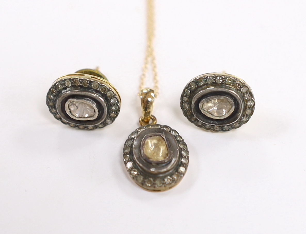 A suite of Indian yellow metal and diamond cluster set suite of jewellery, comprising an oval pendant (overall 22mm), on a 14k chain, 44cm and a pair of matching earrings, 14mm, gross weight 8.2 grams.